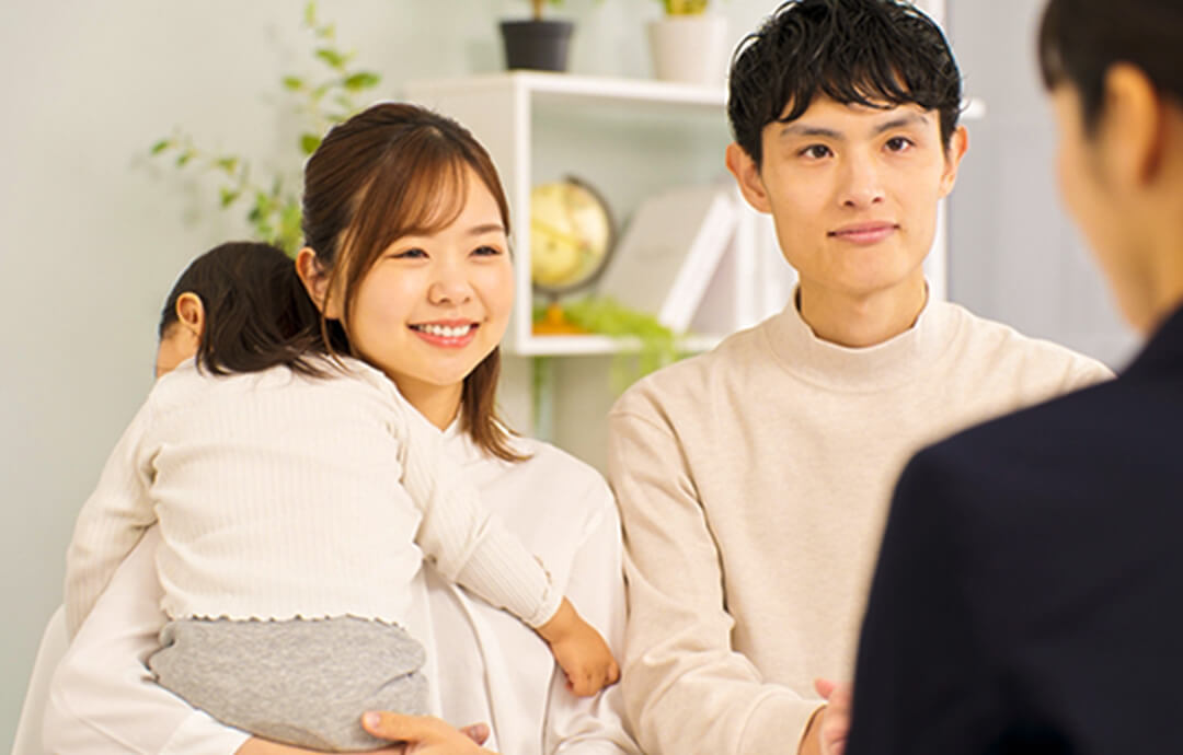 面談室で専門スタッフと話す、子どもを抱いた夫婦の写真。