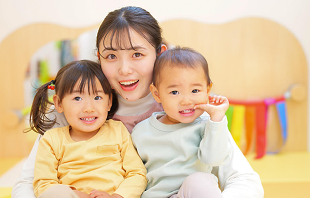 笑顔の女性スタッフと2人の子どもが写っている写真。